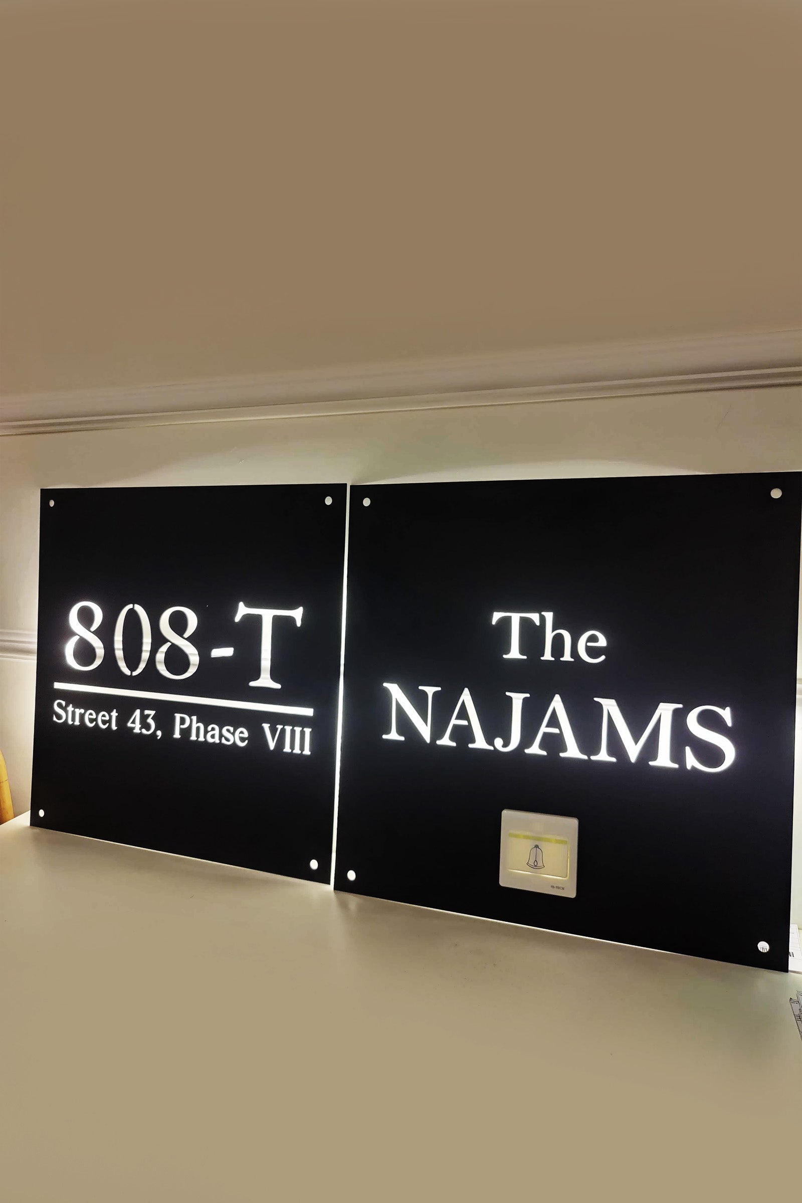 Custom illuminated black acrylic house sign with address and name in white lettering